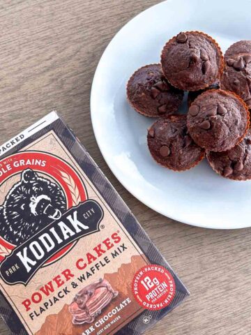 white plate of chocolate banana kodiak muffins and box of kodiak power cakes mix