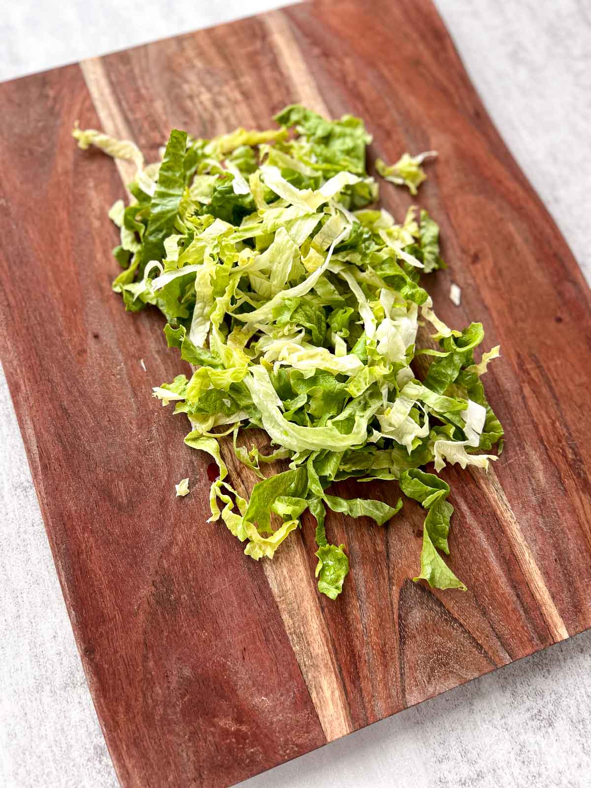 Shredded lettuce on a wood cutting board.