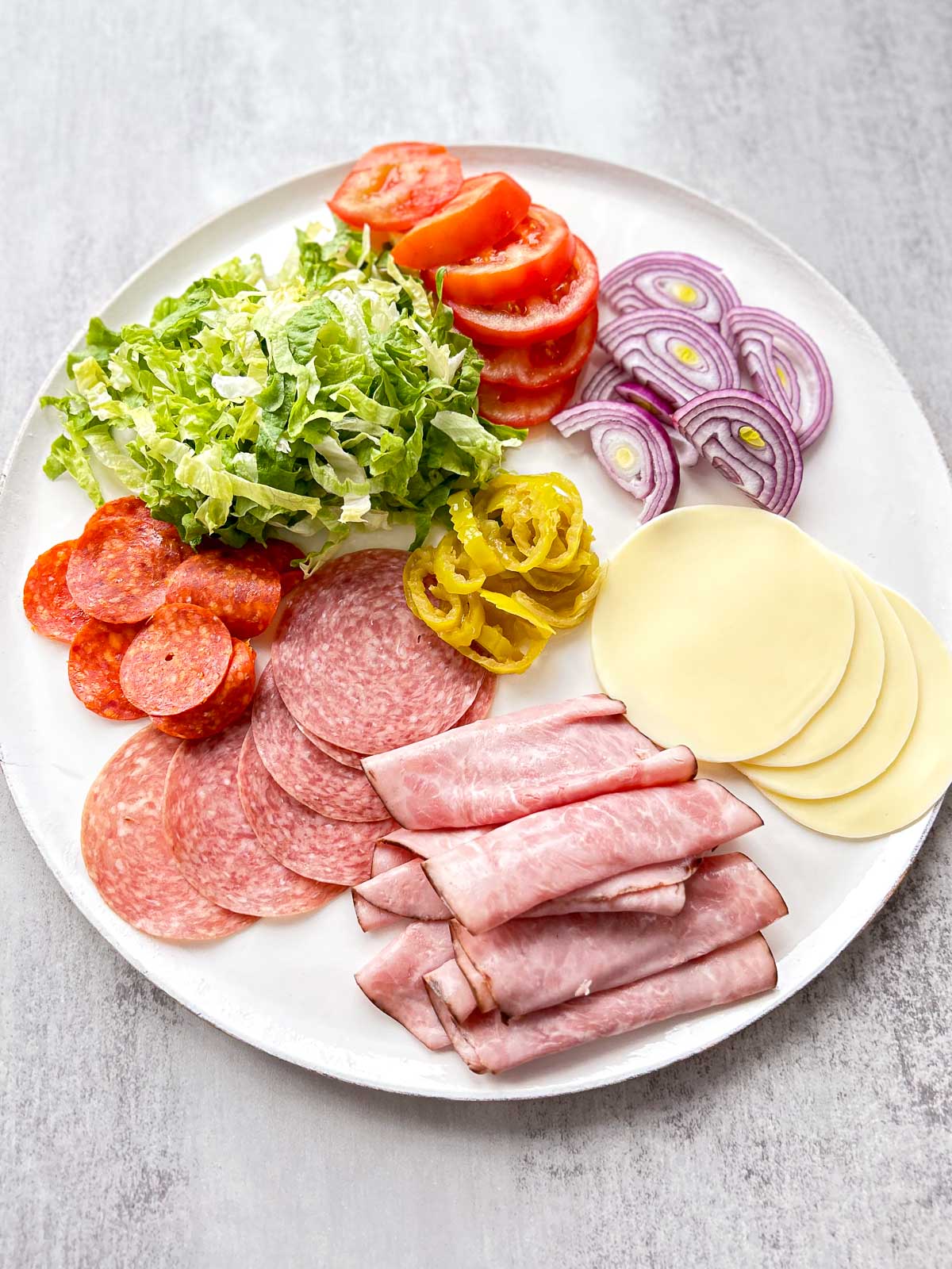 White plate with ingredients to make an Italian chopped salad.